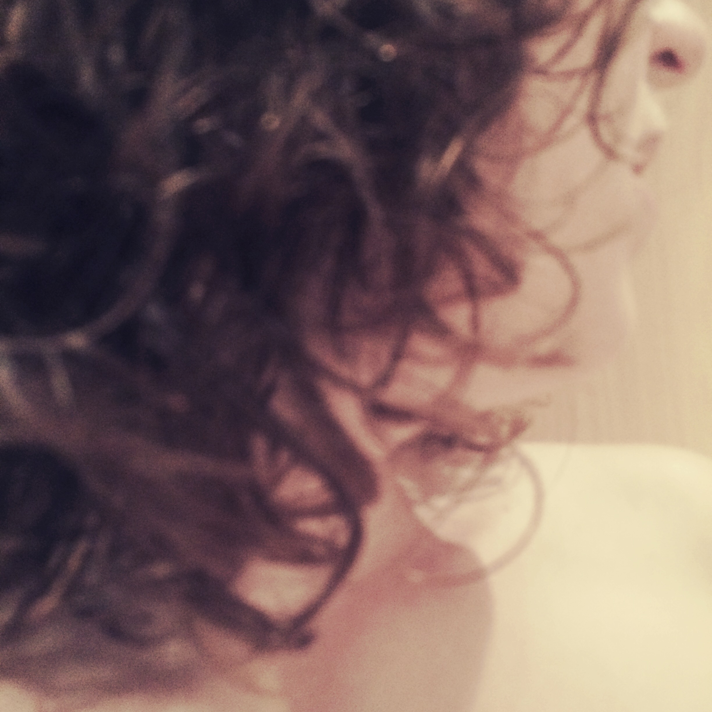 My Twitter avatar - a photo looking over my shoulder with my face obscured by curly brown hair