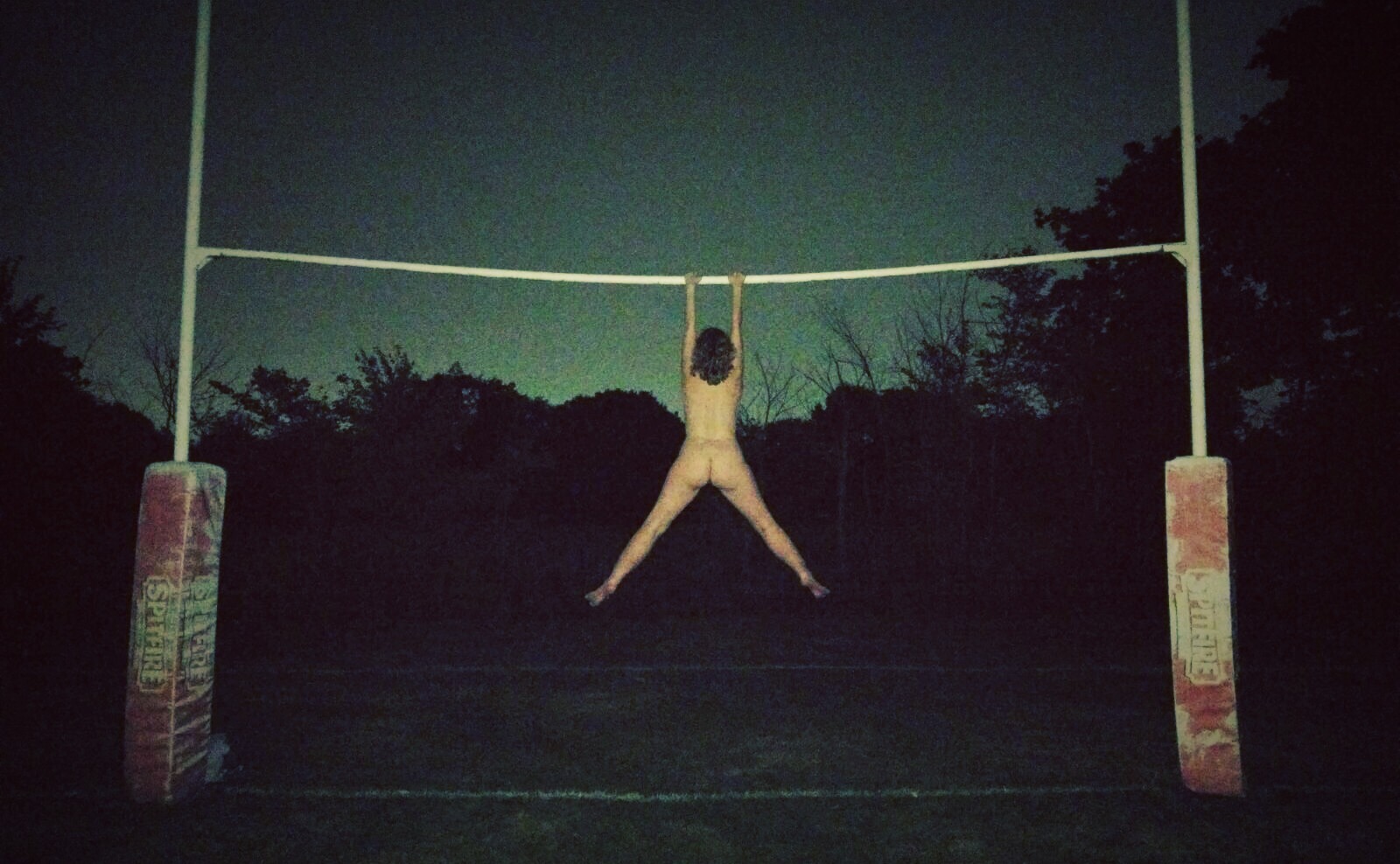 Naked me hanging under the crossbar of a rugby goal